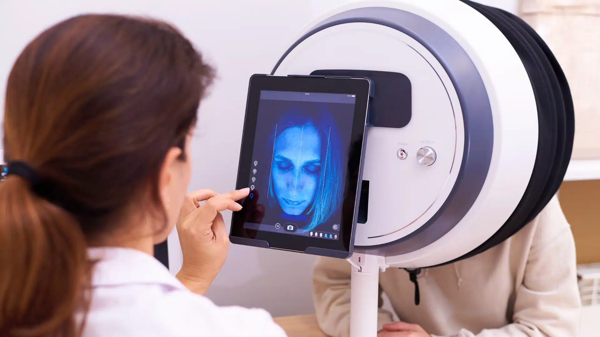 Health Hub 23 Dermatologist analyzing patient’s face with advanced skin scanner and digital imaging technology