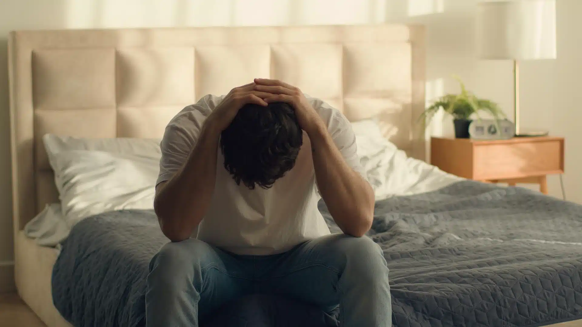 Health Hub 52 Stressed man sitting on bed with head in hands suffering from insomnia or sleep problems
