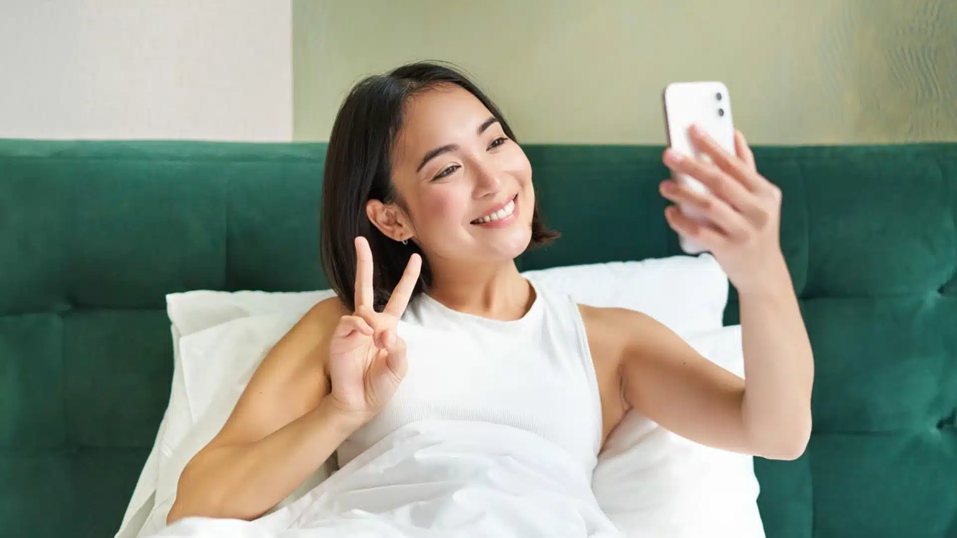 Health Hub 27 Smiling woman in bed taking selfie with peace sign