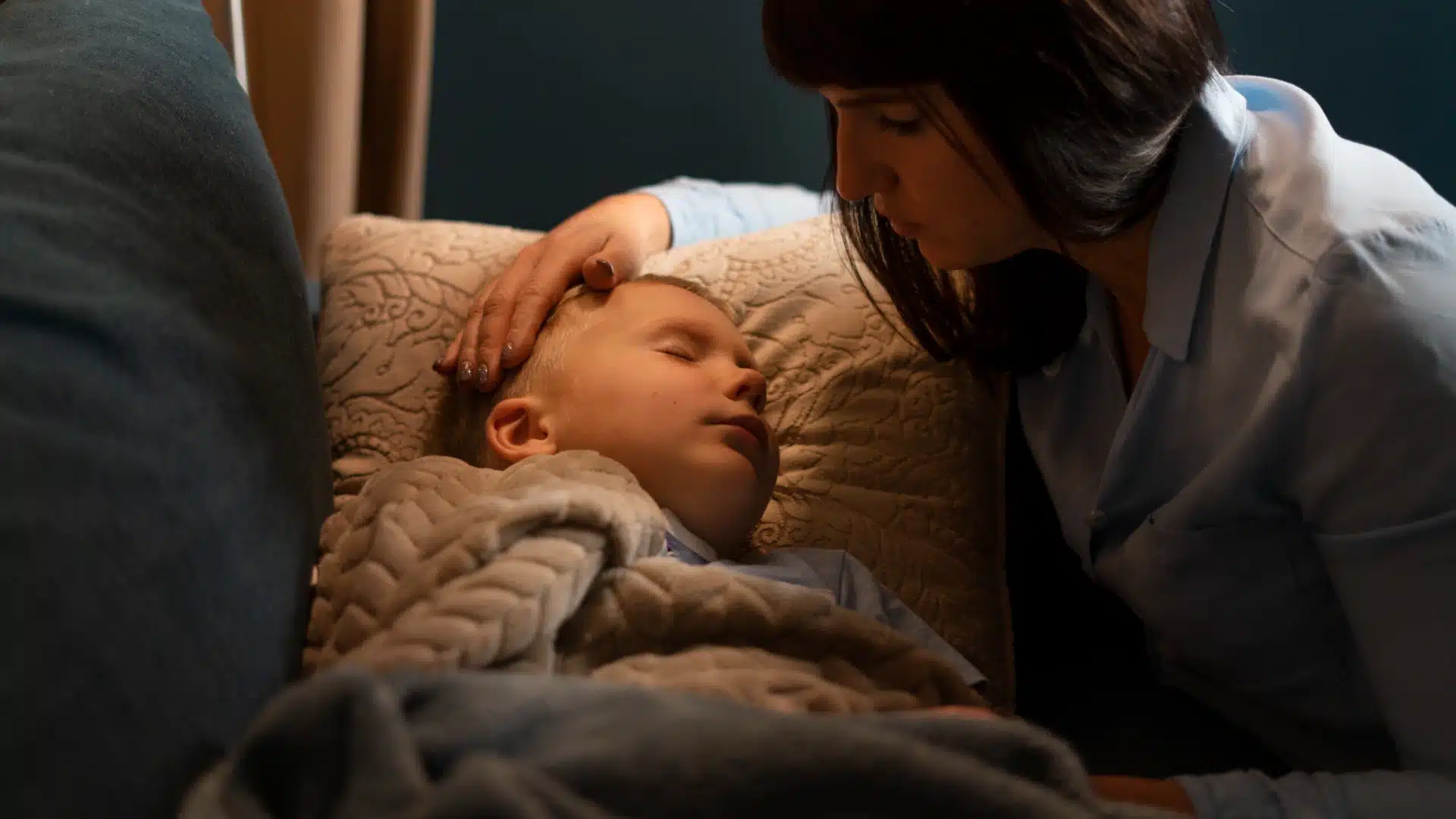 Health Hub 25 Mother gently comforting her sleeping child in bed with warm blanket at night