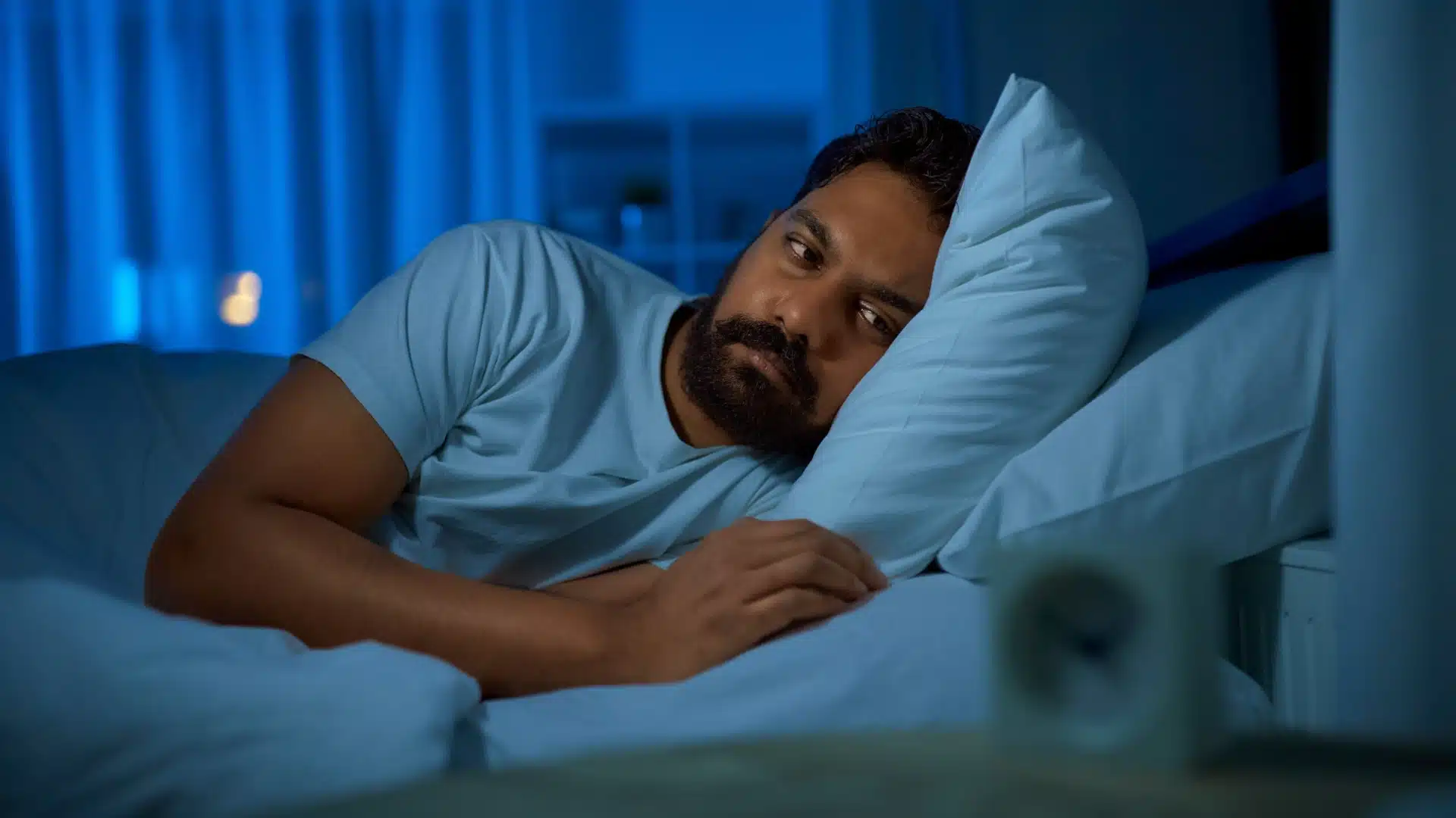 Health Hub 82 Man with insomnia lying in bed at night, unable to sleep and looking restless due to sleep disorder