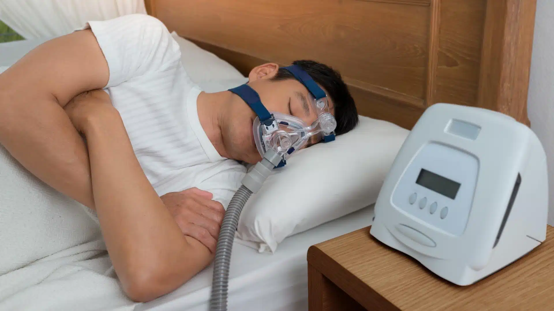 Health Hub 58 Man sleeping with CPAP mask and machine on bedside table