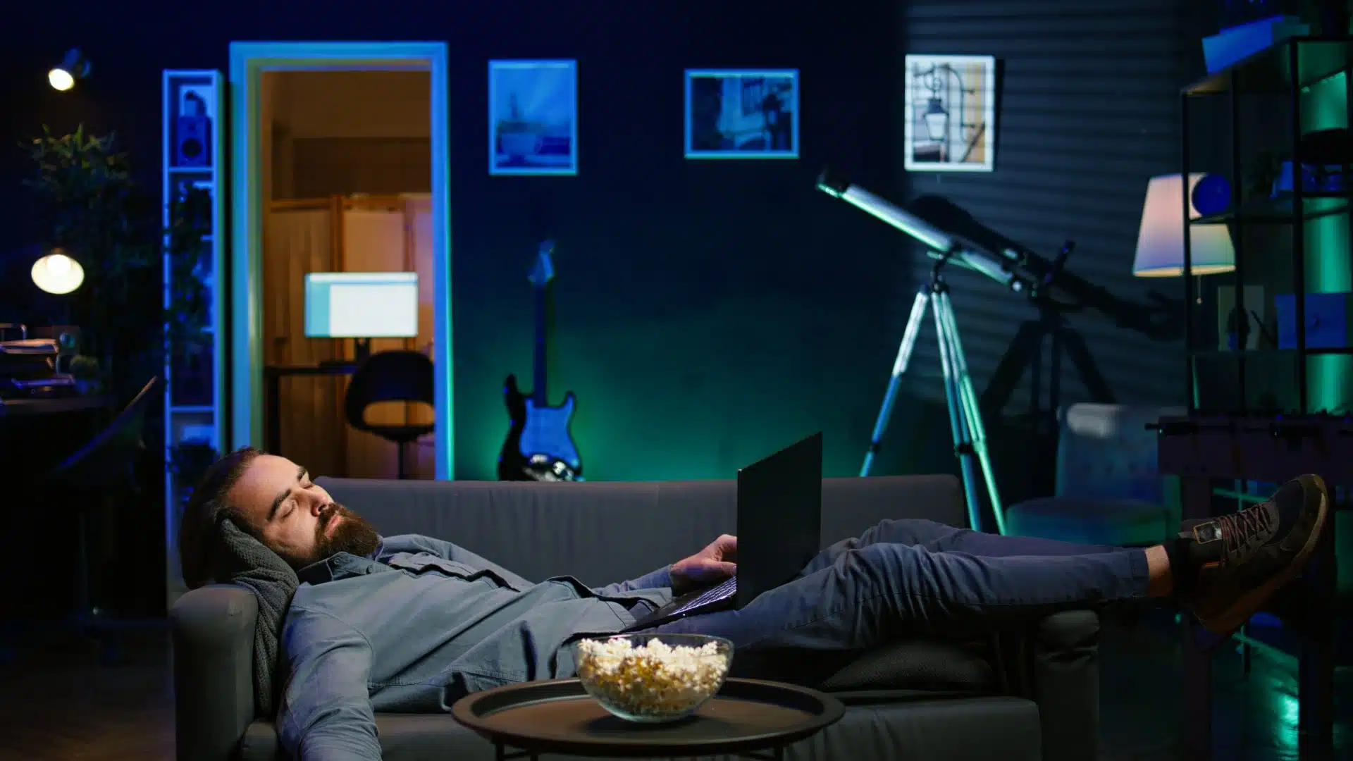 Health Hub 16 Man falling asleep on couch with laptop after working late at night in living room