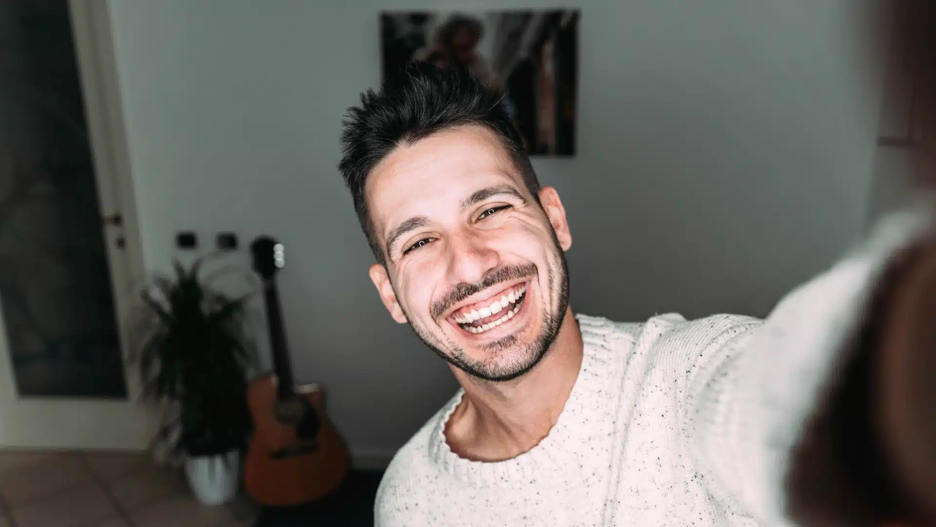 Health Hub 69 Smiling young man taking a cheerful selfie at home in casual sweater
