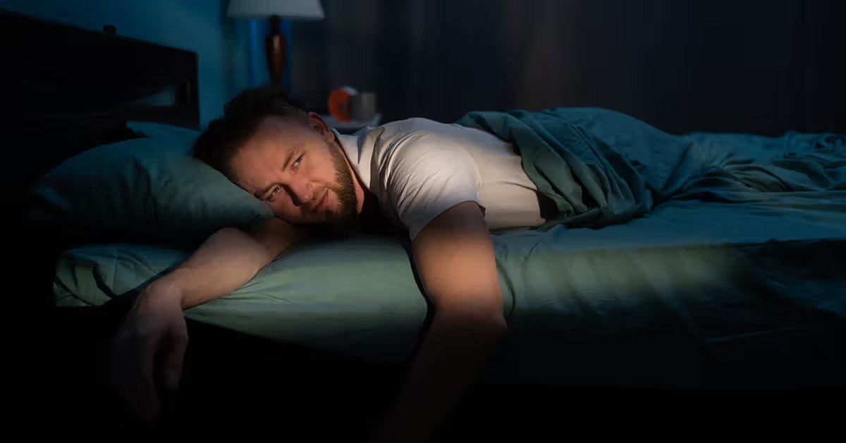 Health Hub 9 Man lying awake in bed at night, looking tired and restless, concept of insomnia and sleep disorders