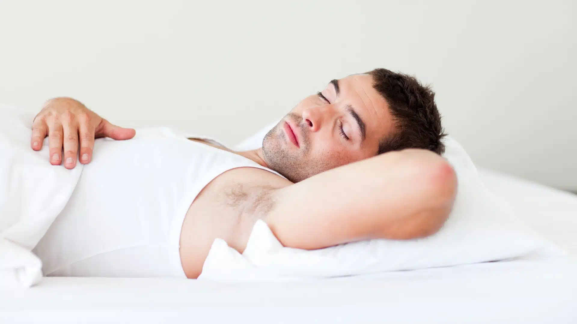 Health Hub 71 Young man sleeping peacefully on white bed in comfortable position with hand on chest