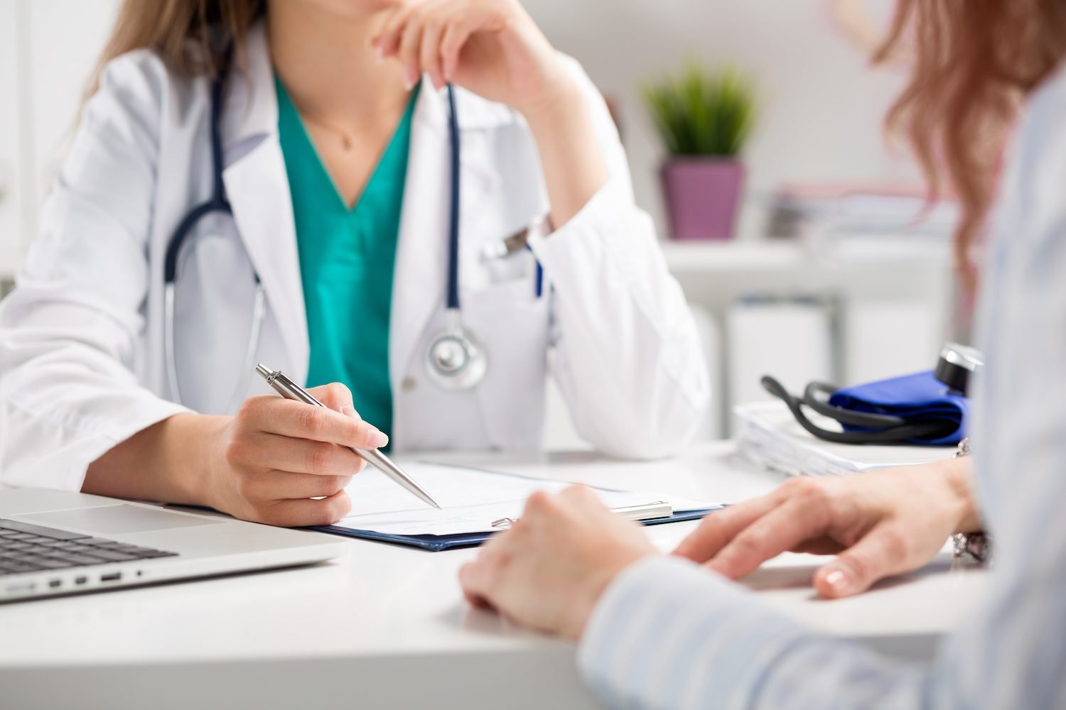 Health Hub 6 Doctor consulting with patient in medical office, writing notes on clipboard during healthcare appointment