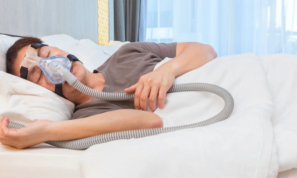 Health Hub 7 Man sleeping with CPAP machine and mask for sleep apnea treatment in bedroom