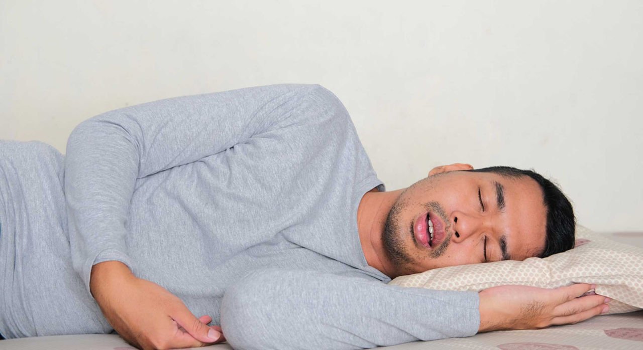 Health Hub 14 Man sleeping on side with mouth open, showing symptoms of snoring or sleep apnea