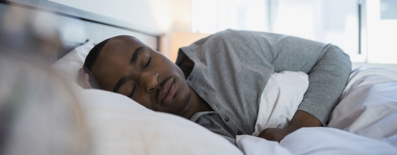 Health Hub 41 Man sleeping peacefully in bed wearing gray shirt showing restful night and healthy sleep